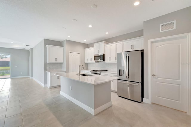 kitchen with white cabinetry, sink, tasteful backsplash, a kitchen island with sink, and appliances with stainless steel finishes