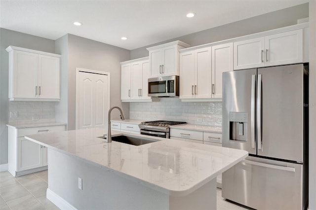 kitchen with an island with sink, stainless steel appliances, white cabinetry, and sink