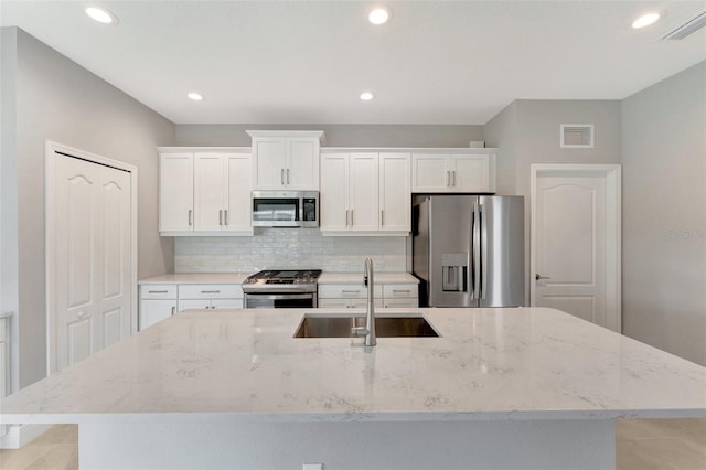 kitchen featuring appliances with stainless steel finishes, a center island with sink, white cabinetry, and sink