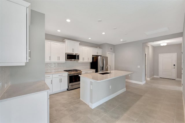 kitchen with white cabinets, sink, stainless steel appliances, and a kitchen island with sink