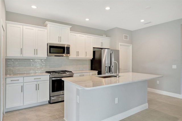 kitchen featuring white cabinets, stainless steel appliances, a kitchen island with sink, and sink