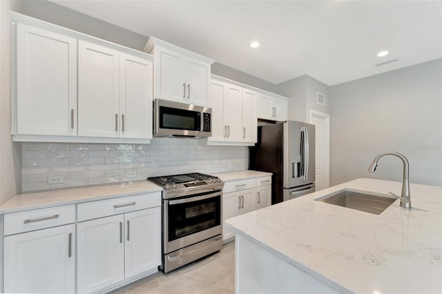 kitchen featuring white cabinets, stainless steel appliances, light stone countertops, and sink