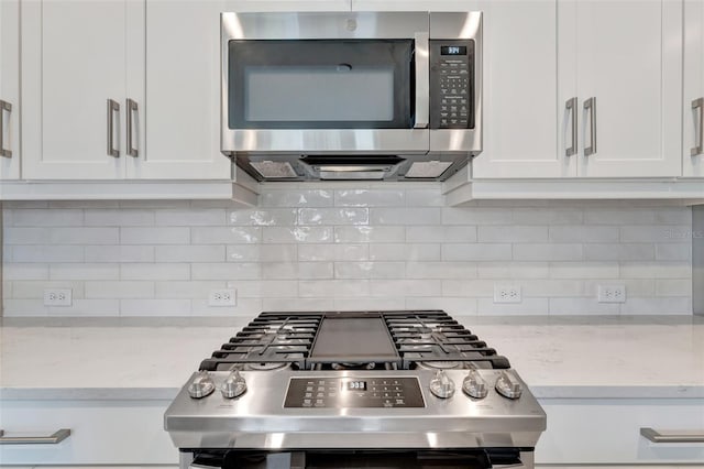 kitchen featuring white cabinetry, light stone counters, range, and tasteful backsplash