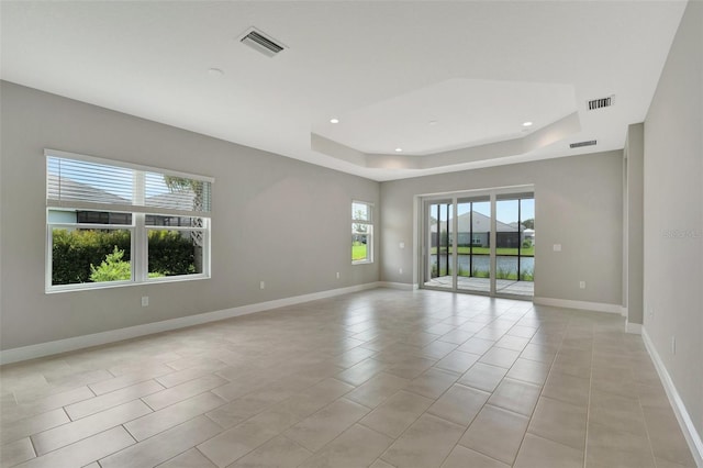 empty room featuring a tray ceiling and light tile patterned flooring