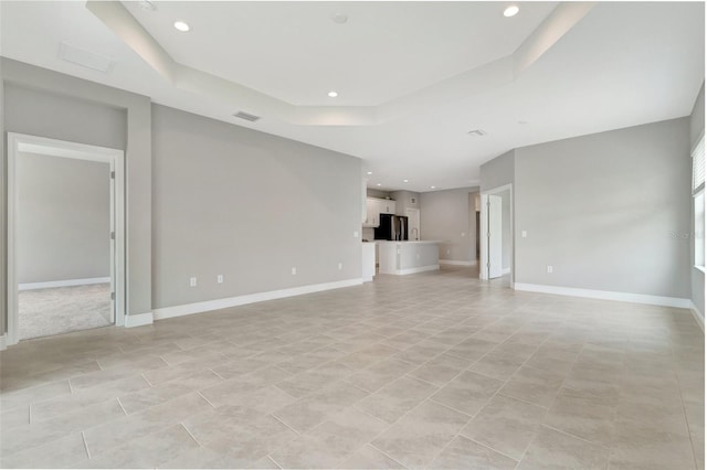 unfurnished living room with a tray ceiling and light tile patterned floors