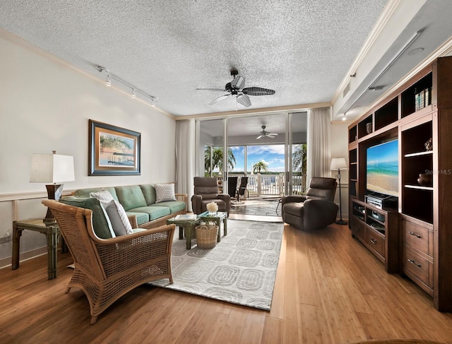 living room featuring ceiling fan, ornamental molding, a textured ceiling, and light hardwood / wood-style flooring