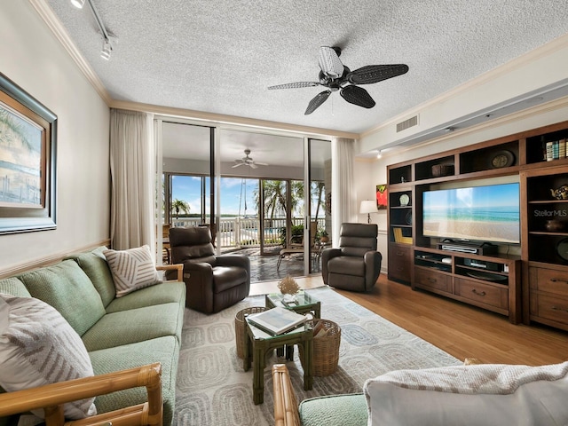 living room featuring track lighting, light hardwood / wood-style flooring, ceiling fan, ornamental molding, and a textured ceiling