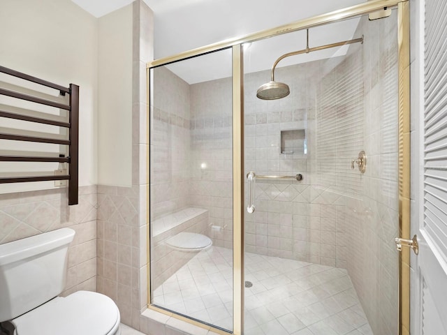 bathroom with toilet, radiator, a shower with shower door, and tile walls