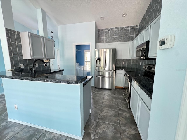 kitchen with stainless steel appliances, decorative backsplash, independent washer and dryer, dark tile patterned flooring, and kitchen peninsula