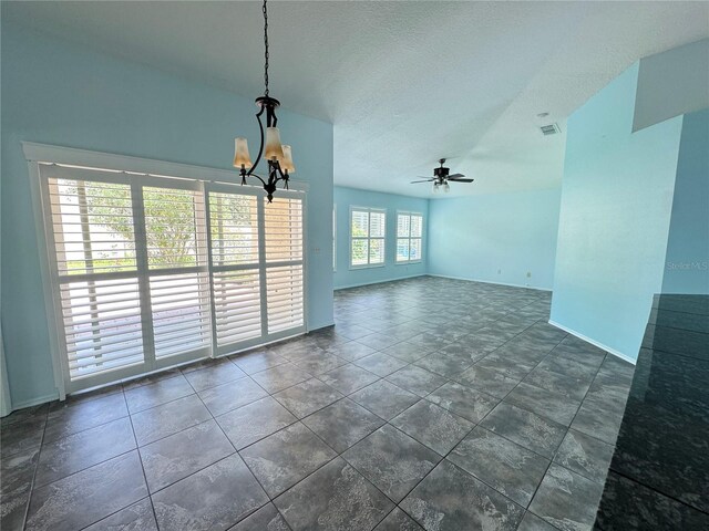 tiled spare room featuring a textured ceiling and ceiling fan with notable chandelier