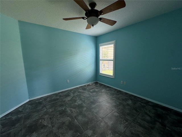 spare room with dark tile patterned flooring, ceiling fan, and a textured ceiling