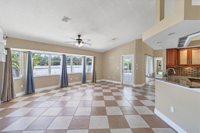 interior space featuring ceiling fan, sink, light tile flooring, vaulted ceiling, and a textured ceiling