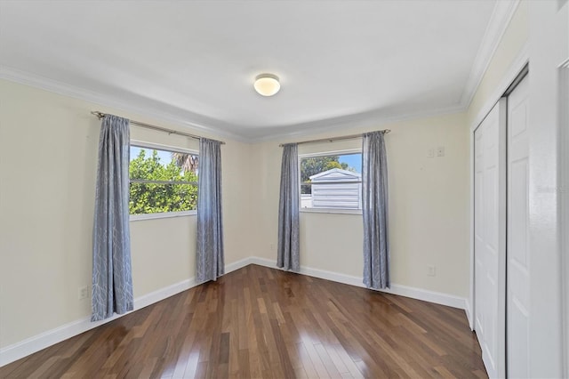 unfurnished bedroom with ornamental molding, a closet, and dark wood-type flooring