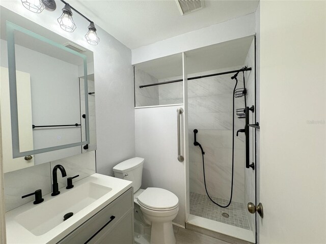 bathroom with vanity, toilet, and a tile shower