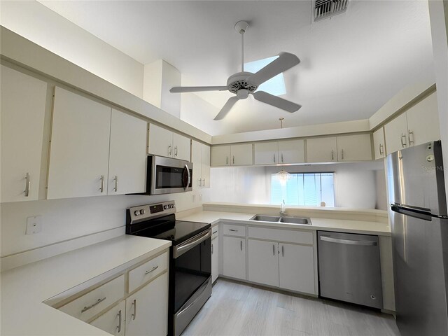 kitchen featuring appliances with stainless steel finishes, sink, ceiling fan, and light hardwood / wood-style floors