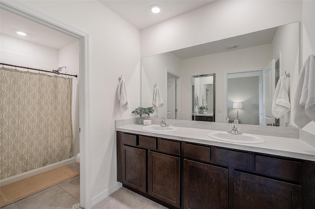 bathroom with tile floors, dual sinks, vanity with extensive cabinet space, and toilet