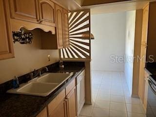 kitchen with stove, light tile floors, and sink