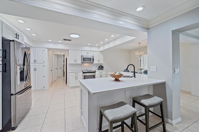 kitchen with an inviting chandelier, white cabinets, a kitchen bar, stainless steel appliances, and backsplash