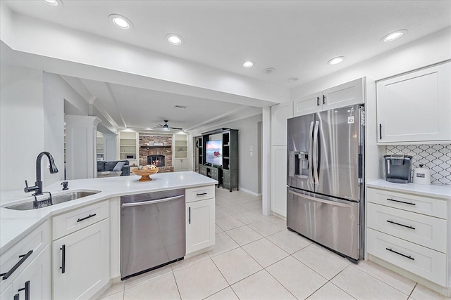 kitchen with ceiling fan, sink, backsplash, stainless steel appliances, and a fireplace