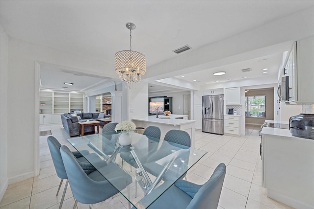 tiled dining area featuring a chandelier, built in features, ornate columns, and sink