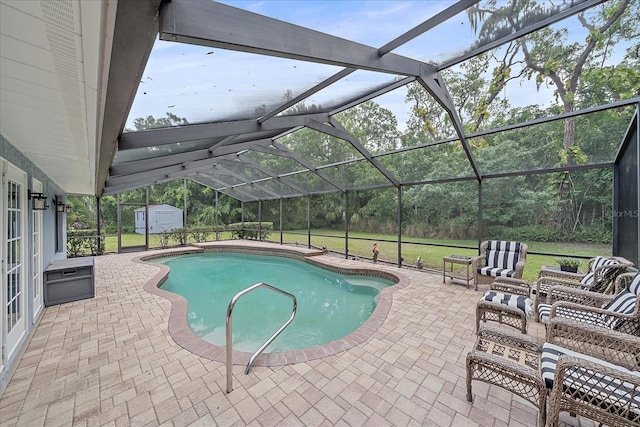 view of pool featuring glass enclosure, a storage shed, a patio area, and a yard