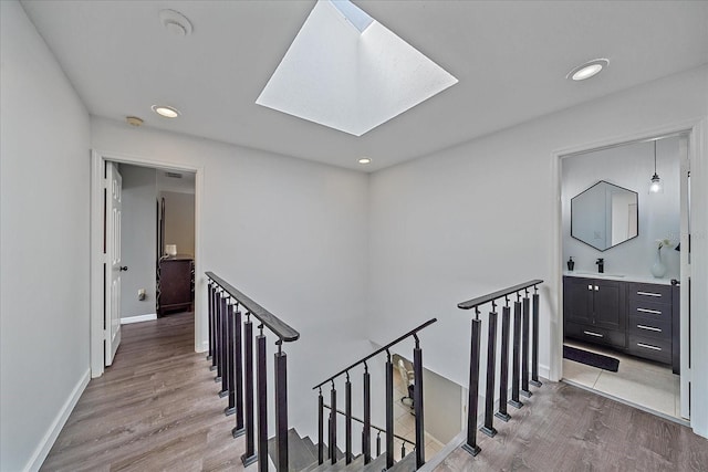 hallway with light hardwood / wood-style floors, sink, and a skylight