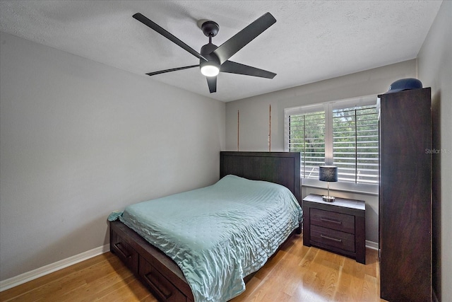 bedroom featuring light hardwood / wood-style flooring, ceiling fan, and a textured ceiling