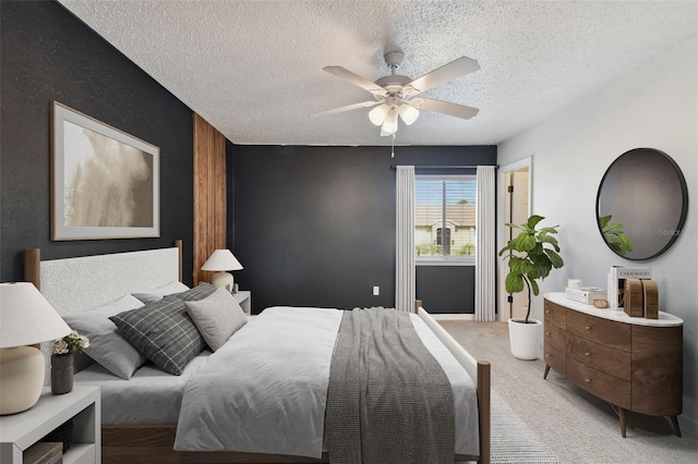 bedroom with ceiling fan, a textured ceiling, and light colored carpet