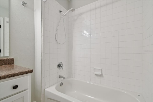 bathroom featuring large vanity and tiled shower / bath combo