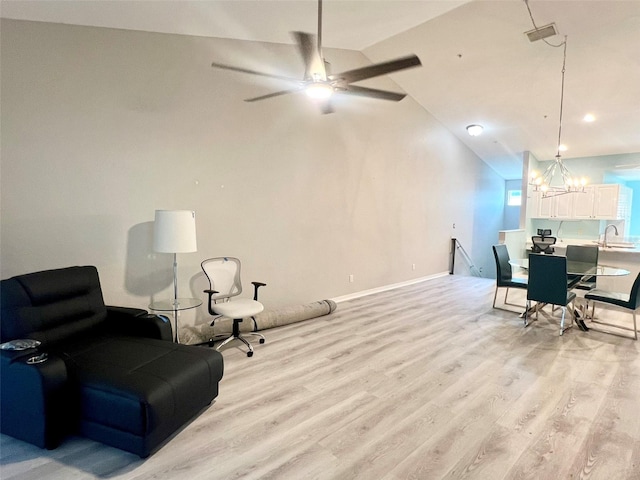 sitting room with vaulted ceiling, light hardwood / wood-style floors, ceiling fan with notable chandelier, and sink