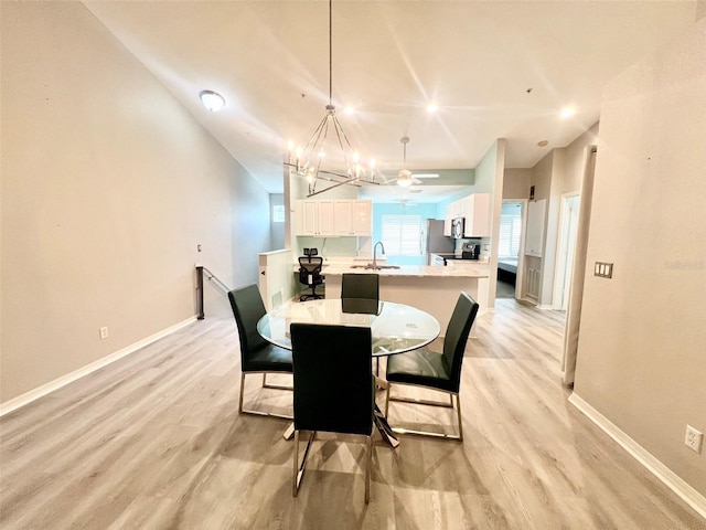 dining space with ceiling fan with notable chandelier, light hardwood / wood-style flooring, and sink