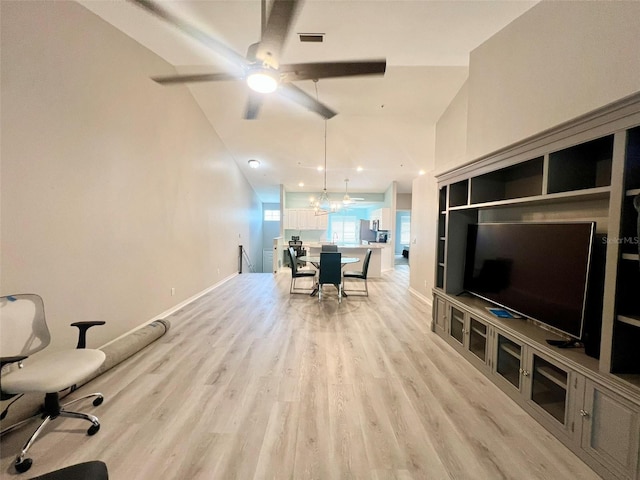 living room featuring ceiling fan with notable chandelier and light hardwood / wood-style floors