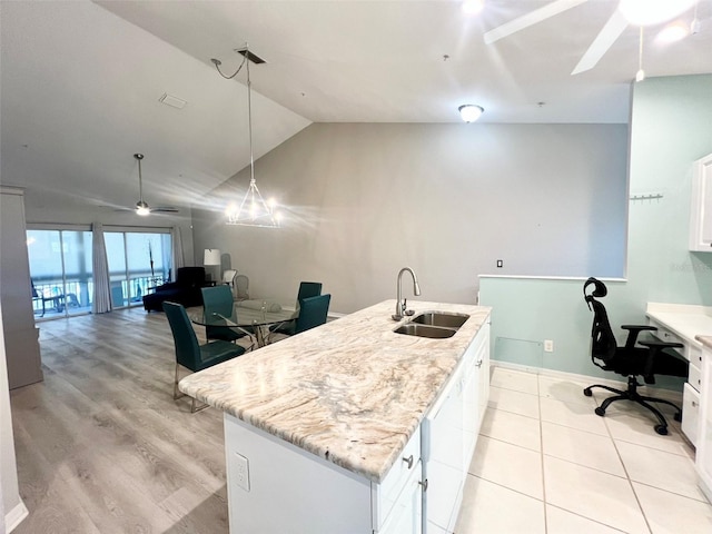 kitchen with white cabinetry, hanging light fixtures, ceiling fan, a kitchen island with sink, and sink