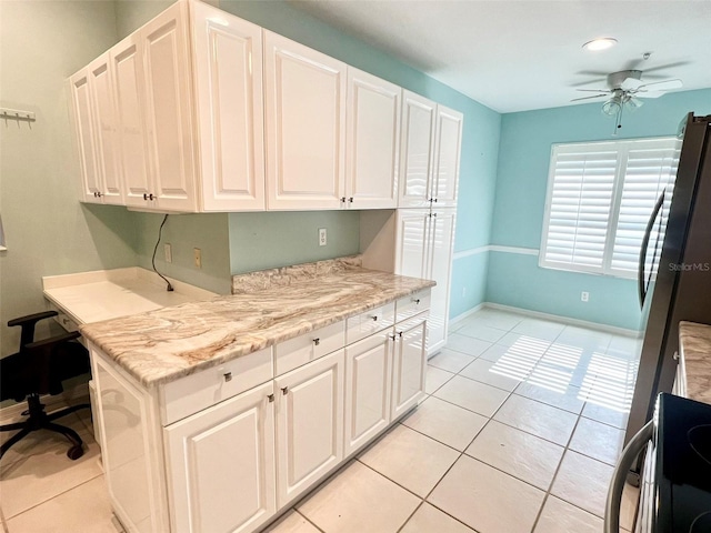 kitchen with white cabinetry, ceiling fan, light tile flooring, light stone counters, and range