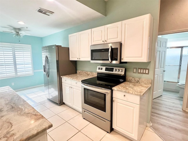 kitchen featuring light hardwood / wood-style floors, stainless steel appliances, ceiling fan, and white cabinets