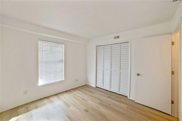 unfurnished bedroom with a closet and light wood-type flooring