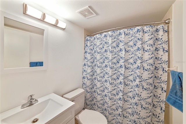 bathroom featuring walk in shower, vanity, and toilet