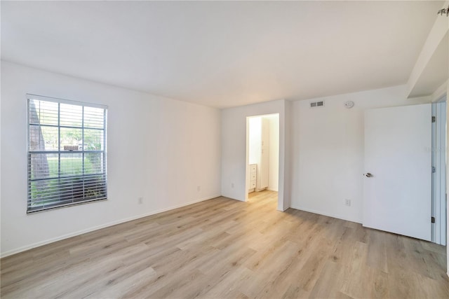 empty room featuring light wood-style floors, visible vents, and baseboards