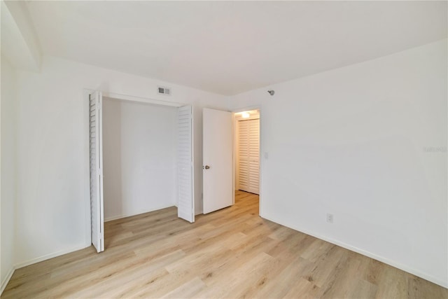 unfurnished bedroom with a closet, visible vents, and light wood-style flooring