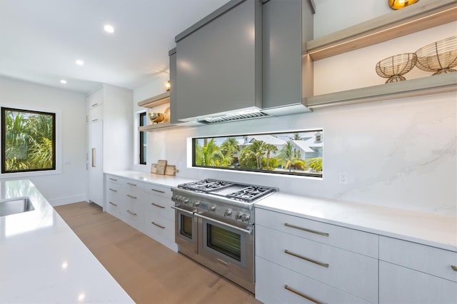 kitchen with range with two ovens, gray cabinetry, and light stone countertops