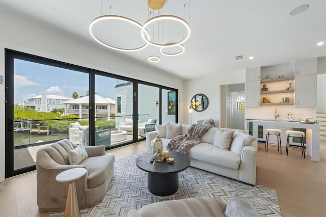 living room featuring a water view, a notable chandelier, and light hardwood / wood-style floors