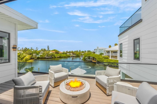 wooden deck with an outdoor living space with a fire pit and a water view