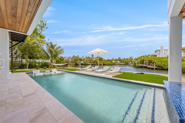 view of swimming pool with a water view, a lawn, and a patio area