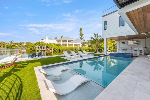 view of swimming pool featuring a patio area, exterior kitchen, a lawn, and a water view