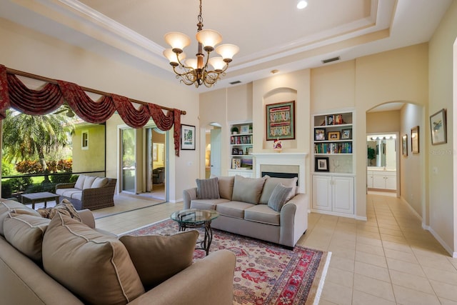 living room featuring light tile floors, a notable chandelier, a tray ceiling, and built in features