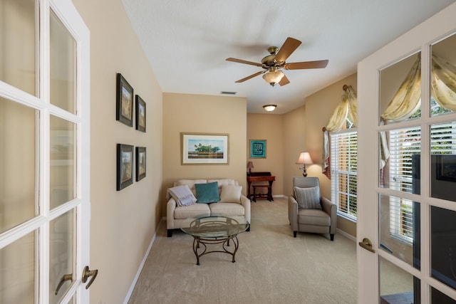 living area with ceiling fan and carpet