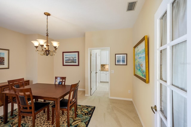 carpeted dining room featuring a notable chandelier