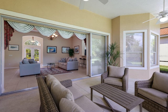 tiled living room with french doors and ceiling fan with notable chandelier