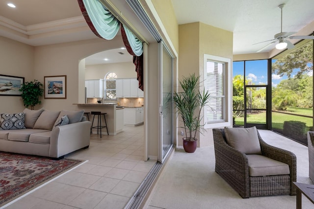 tiled living room featuring ceiling fan and a raised ceiling