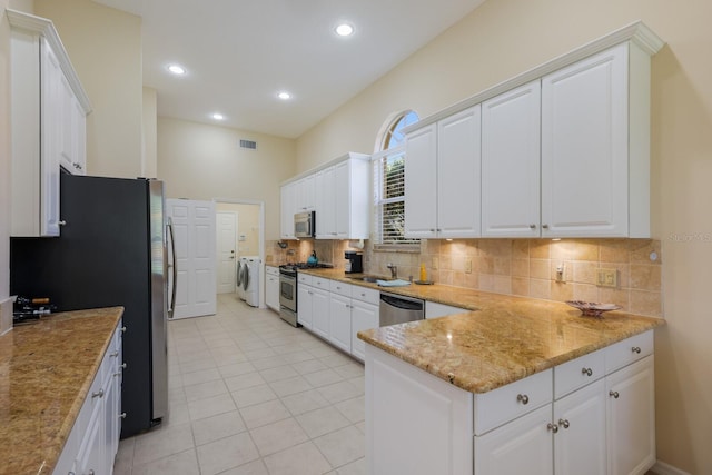 kitchen with washer and clothes dryer, appliances with stainless steel finishes, and white cabinets